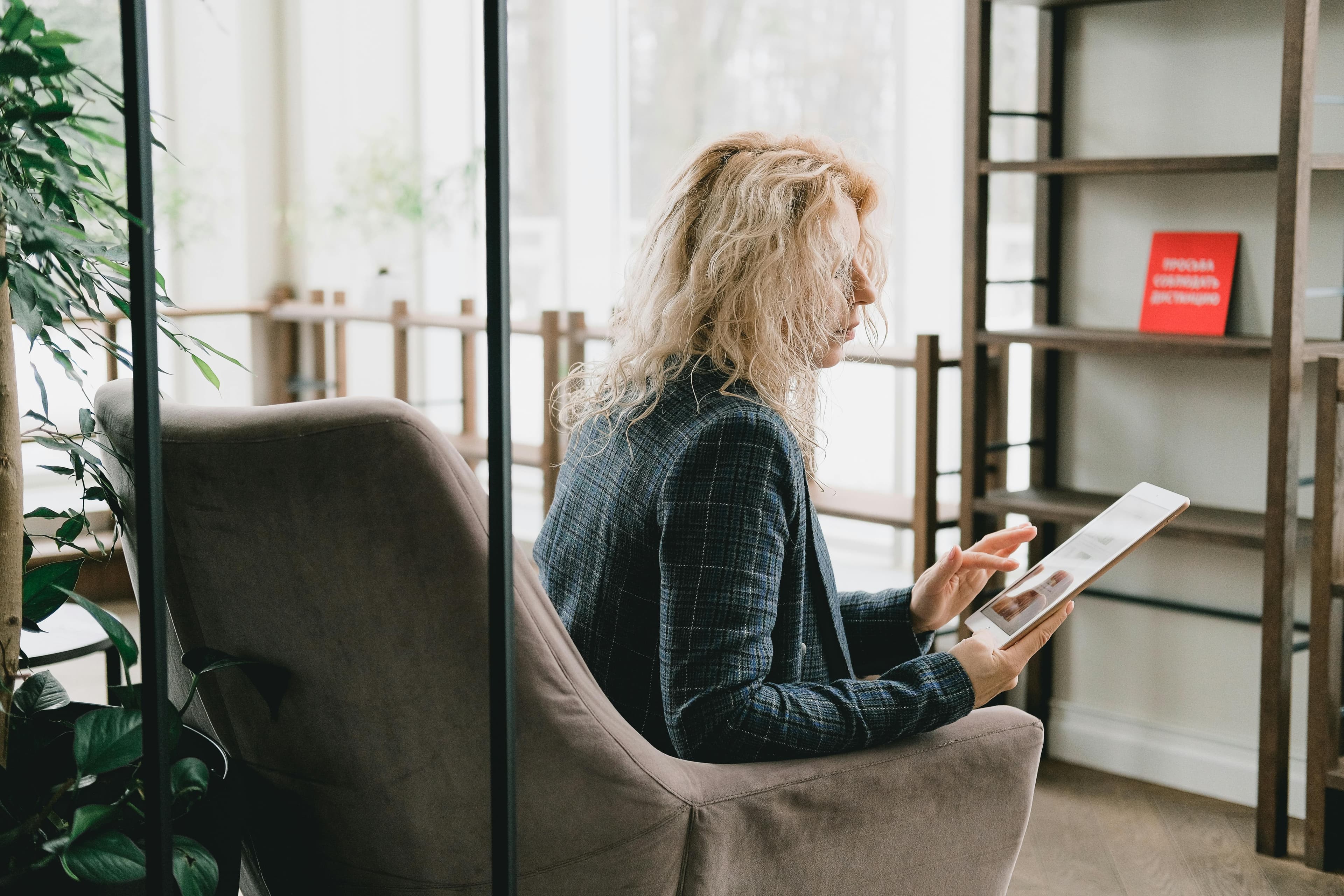 A professional woman sitting in a modern office environment, working on a tablet, representing copywriting jobs