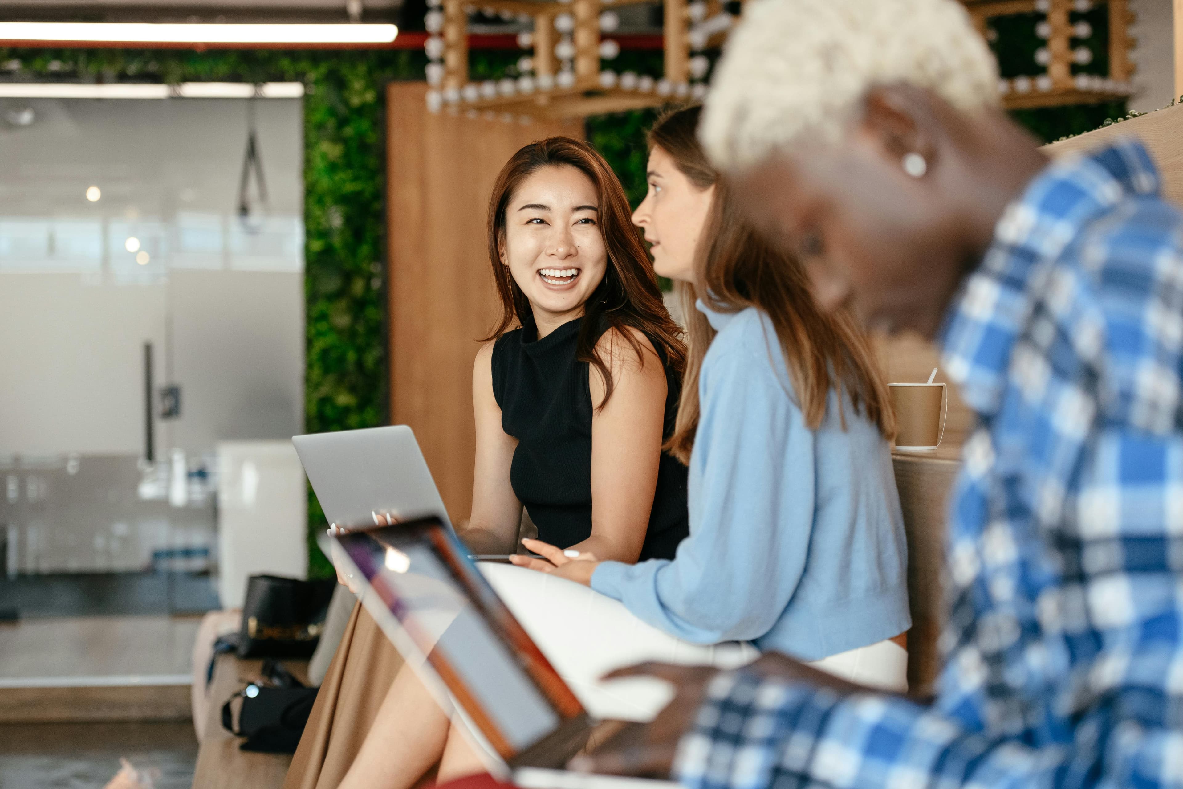 Group of colleagues working on laptops and chatting in a modern office with green decor, representing conversion marketing.