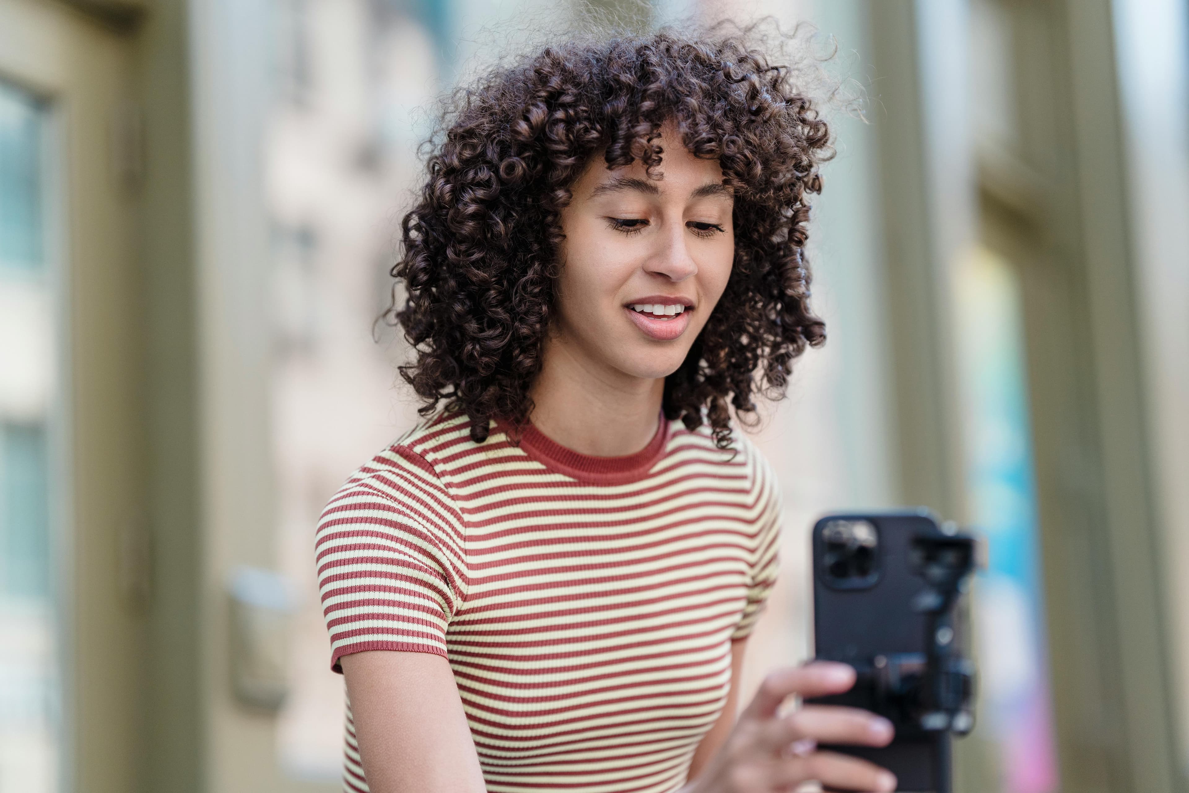 A young woman recording content outdoors with a smartphone, sharing her experience using a "free AI landing page generator" to simplify the process of building effective landing pages.