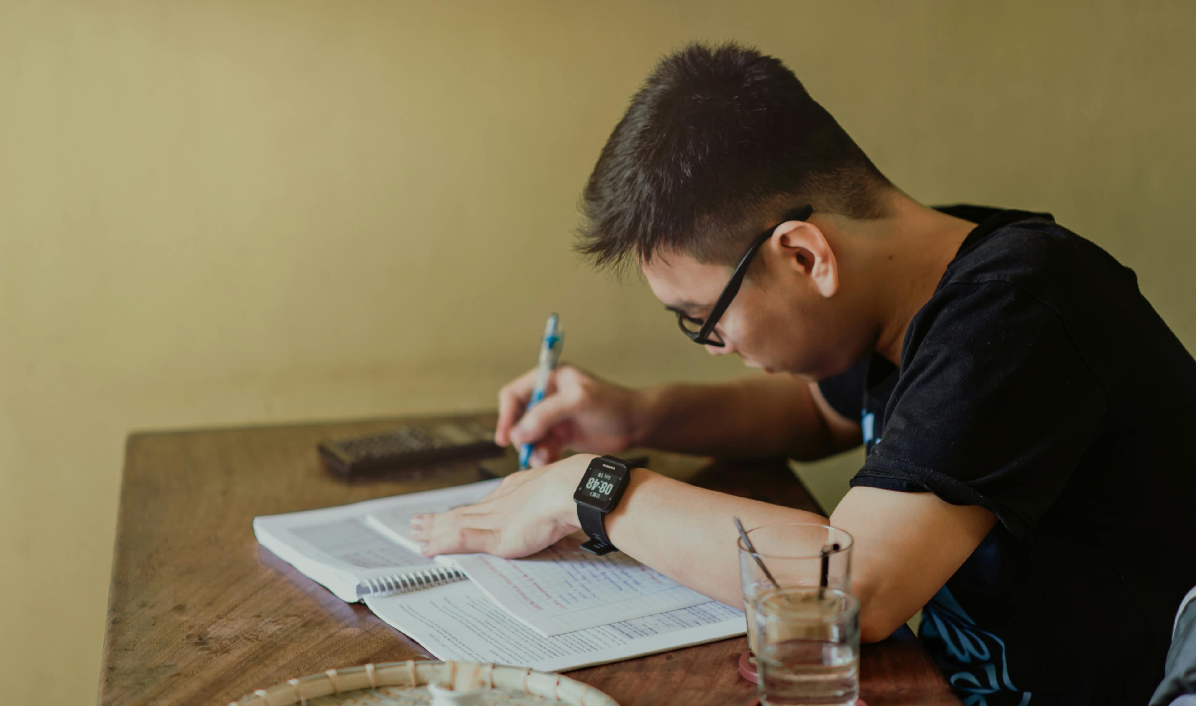 A man deeply engrossed in note-taking and research, representing thorough preparation for a "competitive marketing strategy."