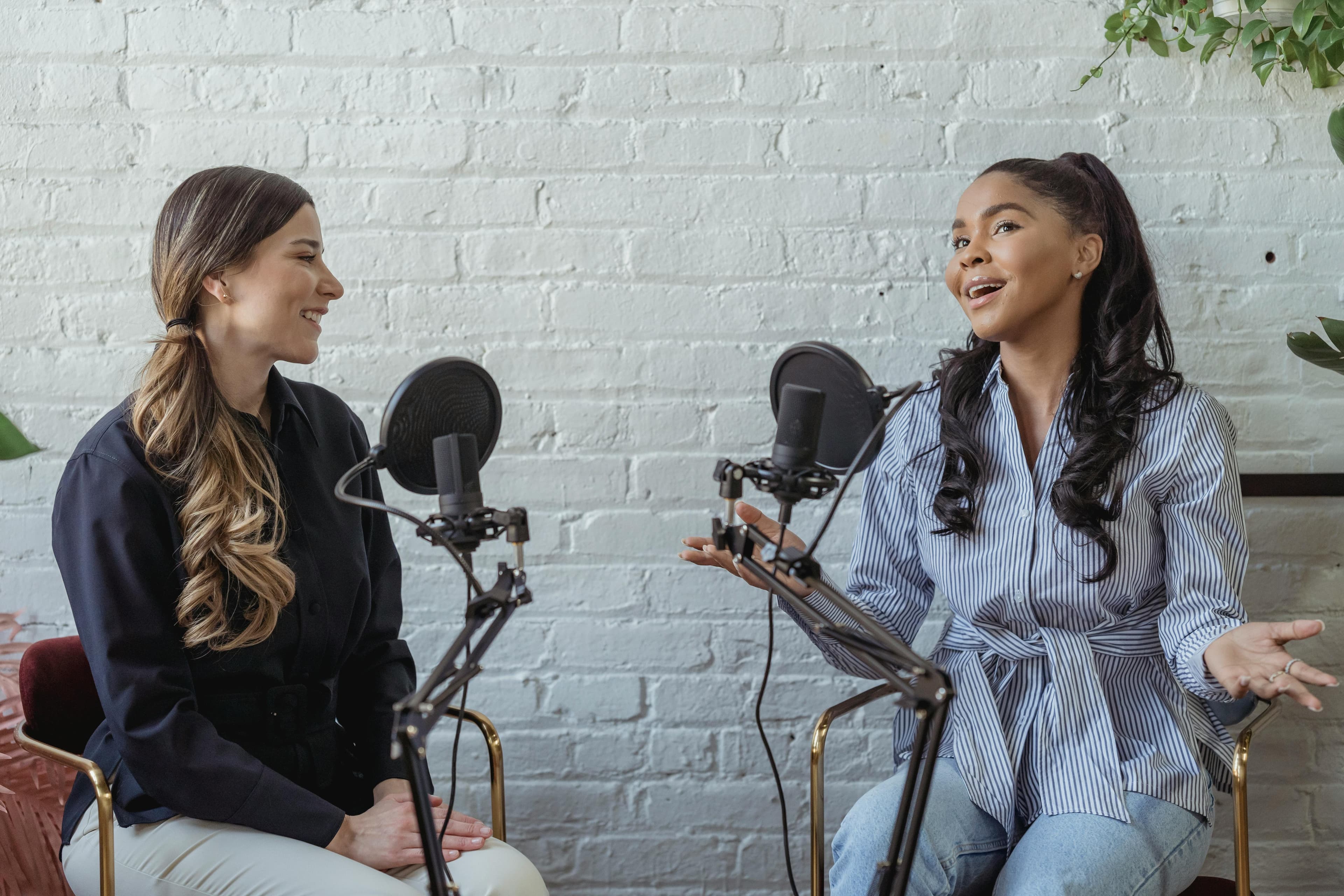 Two women engaged in a podcast recording session, showcasing dynamic interaction and collaboration. The scene emphasizes the **benefits of PPC advertising** in targeting specific audiences effectively and fostering meaningful conversations.