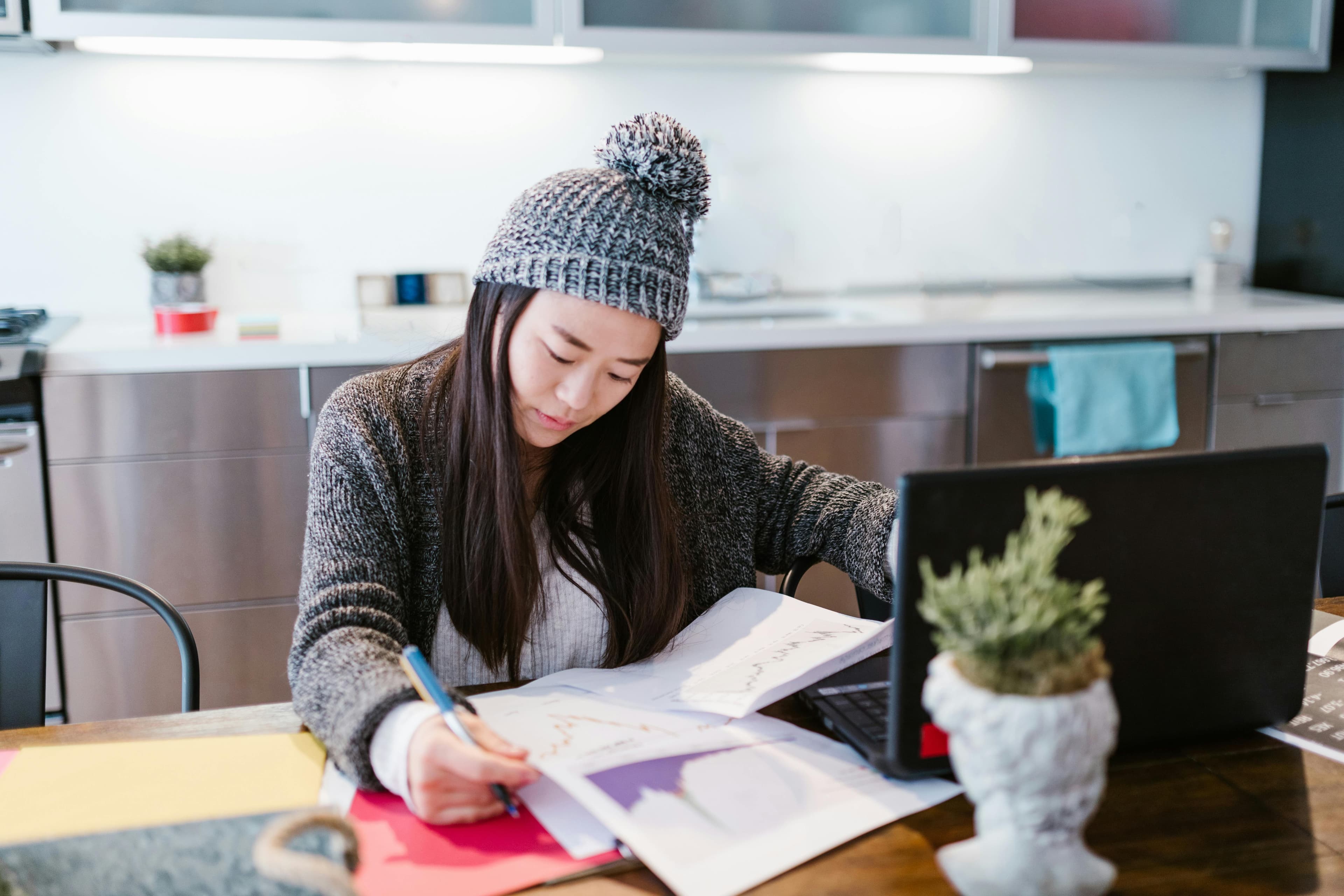 a focused individual working at a desk, reviewing documents while using a laptop. This could symbolize deep analysis and data-driven strategies for conversion rate optimization, involving testing, refining, and optimizing digital assets to boost user engagement and conversions.