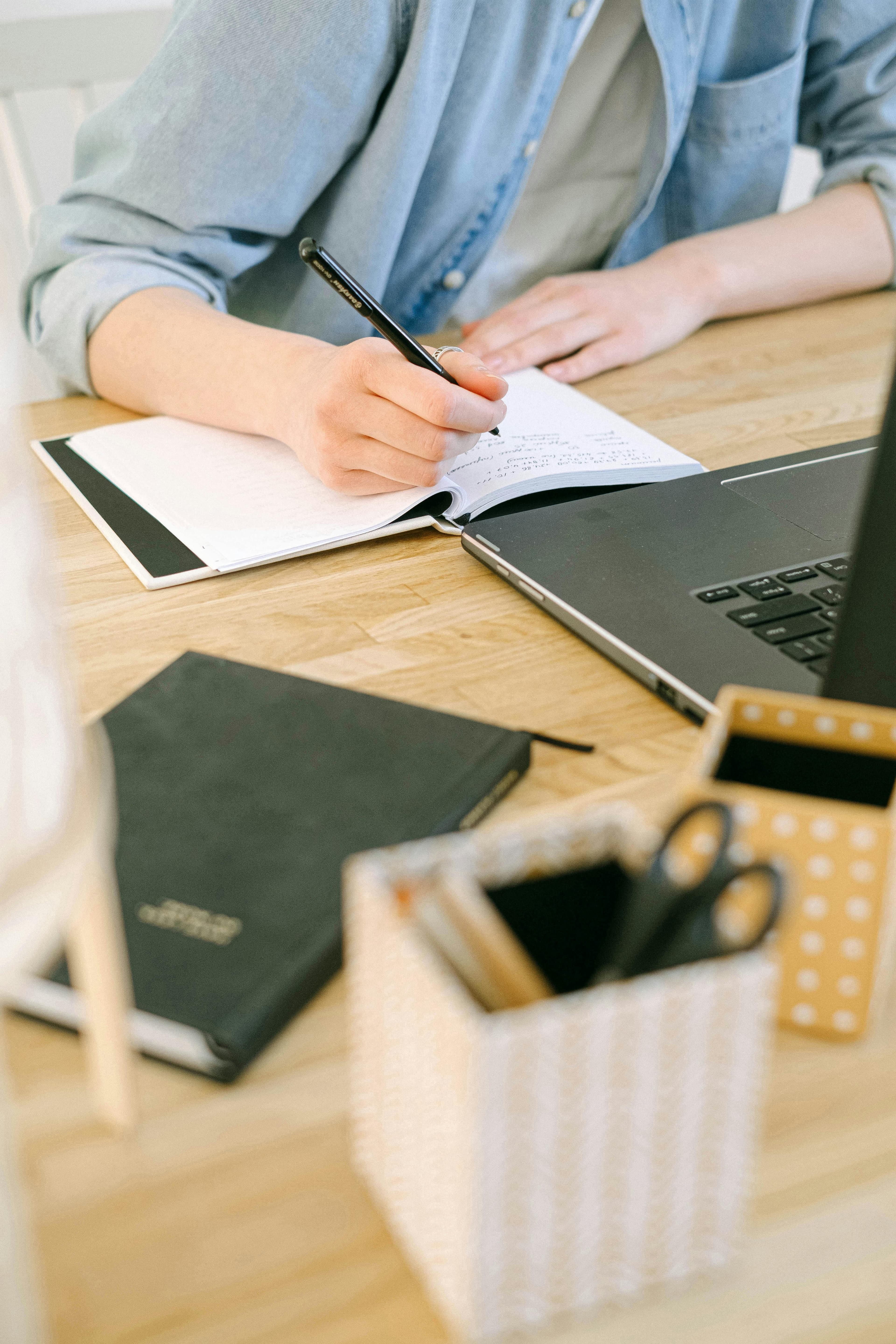 A close-up of a person taking detailed notes in a notebook while working next to a laptop. This scene demonstrates effective brainstorming for creating the best lead generation landing pages.