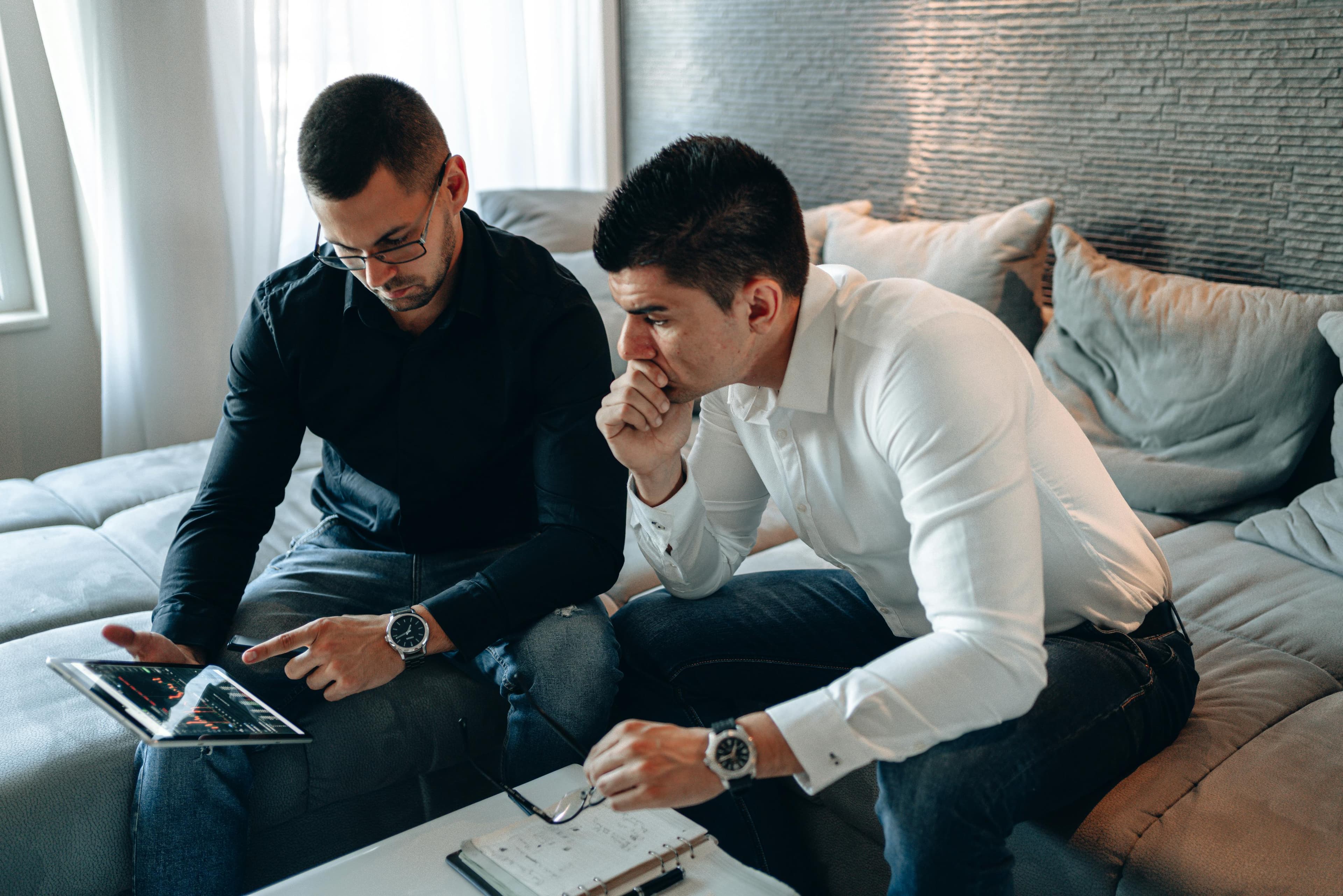 Two men in a modern office setting, deeply focused on analyzing data on a tablet, representing the conversion AI market