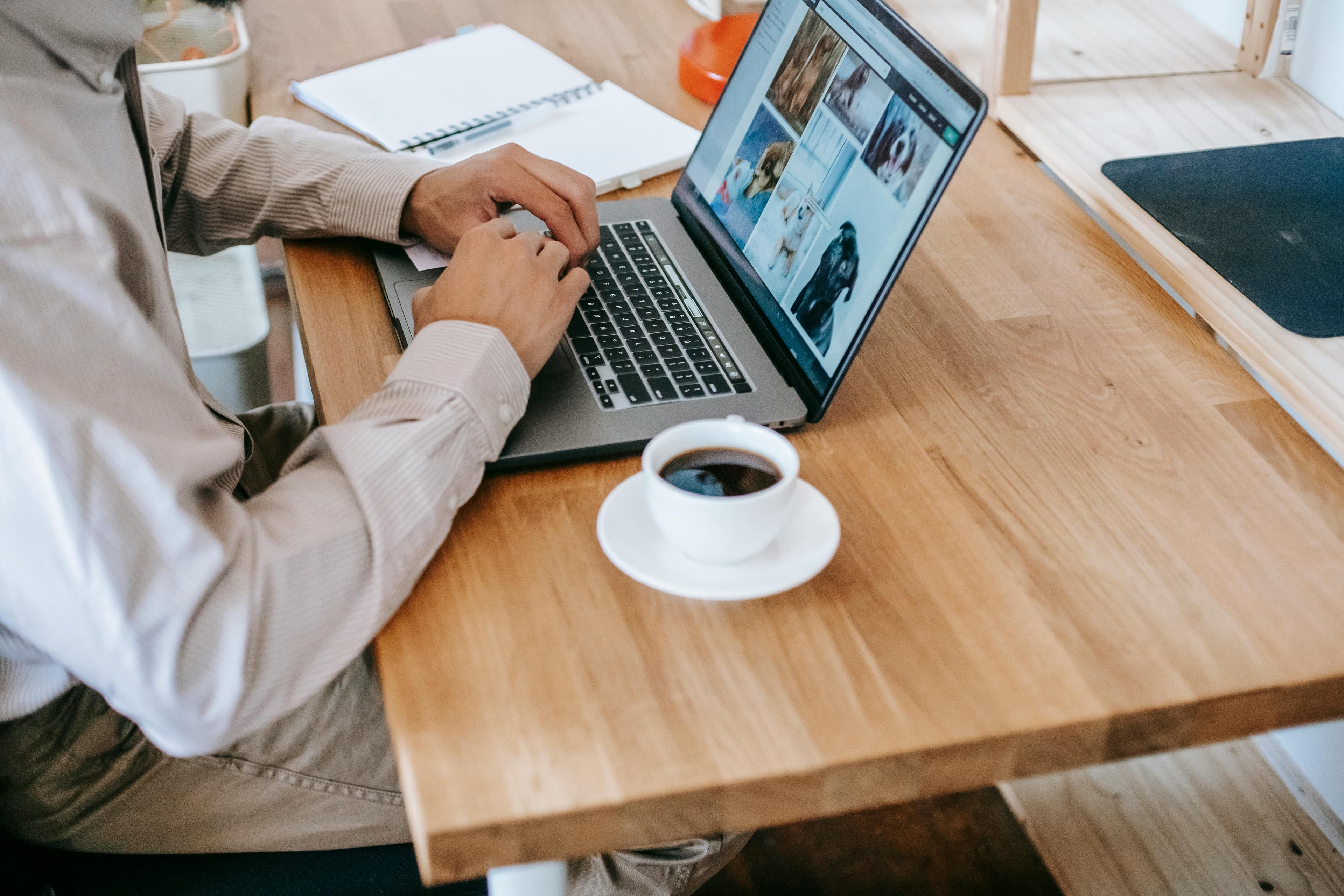 A close-up of a person typing on a laptop with a cup of coffee nearby, illustrating the detailed work involved in processing marketing data analytics during a typical workday.