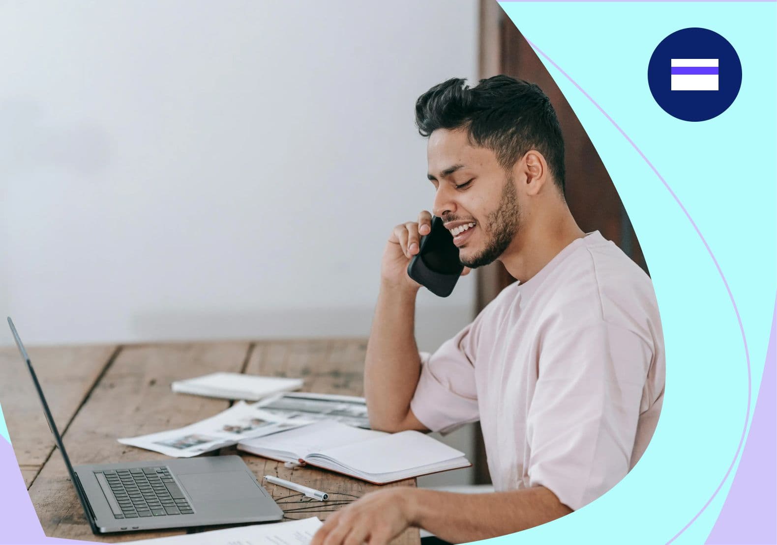 Image of male in the financial services marketing sector on the phone at his desk with papers and a laptop in front of him