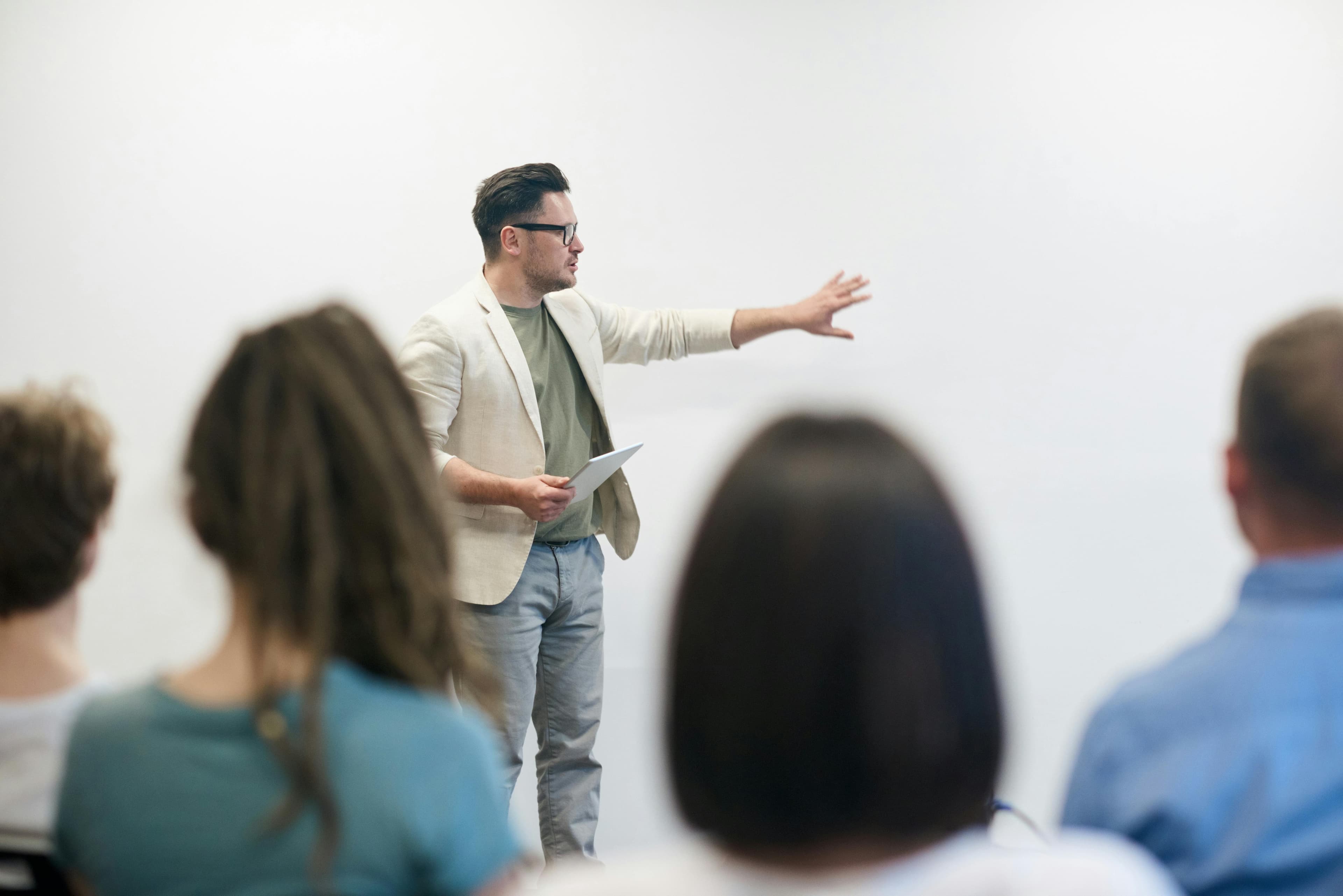 A professional presenter delivering a talk to an audience, gesturing towards a whiteboard during a business workshop. Highlights concepts related to B2B marketing automation and strategy development.