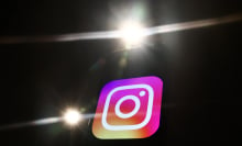 The Instagram logo on a black background. Bright camera flashes light up around it.