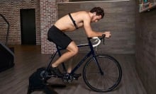 shirtless man wearing chest heart rate monitor on exercise bike