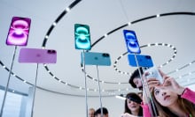 A woman takes a photo of iPhone 16 display models