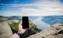 A person holds a phone up toward the horizon in a remote area.