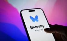 Bluesky app on a smartphone in front of a desktop screen