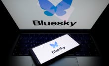 A glowing laptop screen and phone screen both display the Bluesky logo.