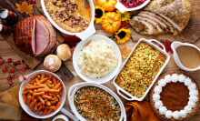 a thanksgiving table spread. there's turkey, ham, mashed potatoes, stuffing. rolls, green bean casserole, cranberry sauce