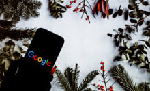 a phone displaying the Google logo surrounded by boughs of holly and such