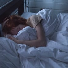 Person in bed holding blankets, asleep