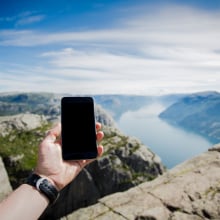 A person holds a phone up toward the horizon in a remote area.