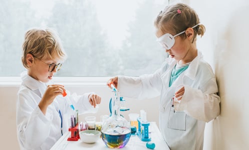 A girl and boy play with a lab science kit.