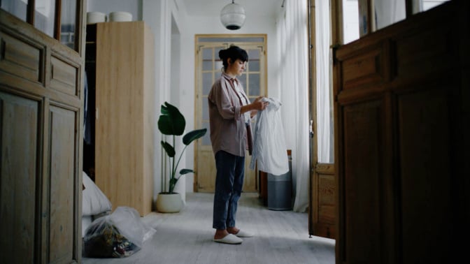 Woman standing in laundry room holding white shirt