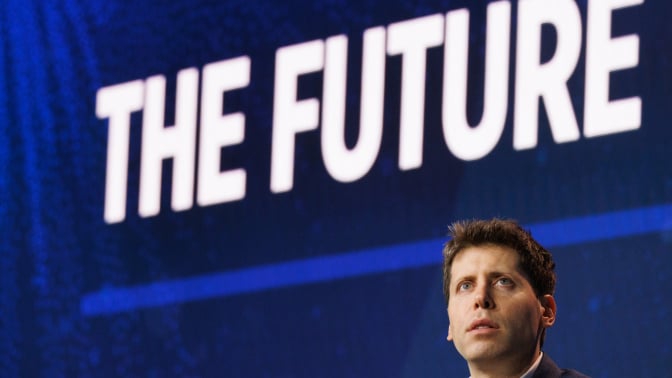 Sam Altman sits under a large screen that reads "The future."