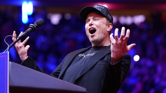 Elon Musk screaming at a Trump rally wearing a 'dark MAGA' hat