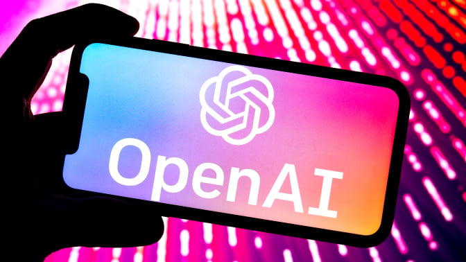 OpenAI logo open on a phone bathed in pink light. 