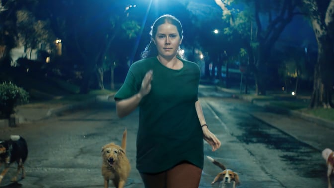 Amy Adams as Mother in "Nightbitch," running at night with dogs.