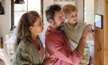 family of three looking at a smart thermostat